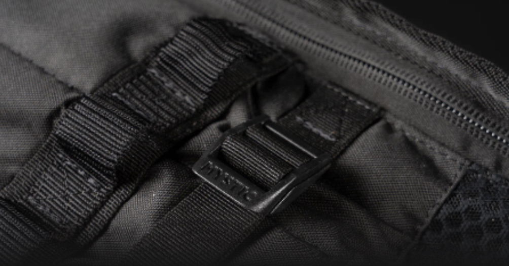 Nahaufnahme eines Gurtbands mit Schnalle neben dem Reißverschluss einer schwarzen Boardbag