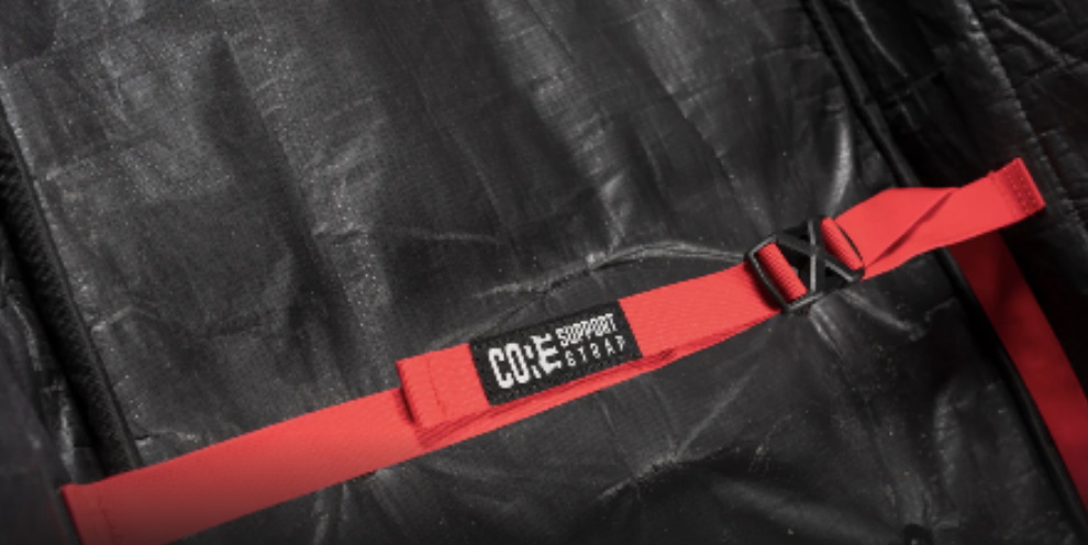 Roter Kompressionsgurt mit der Aufschrift Core Support Strap über einer schwarzen Boardbag