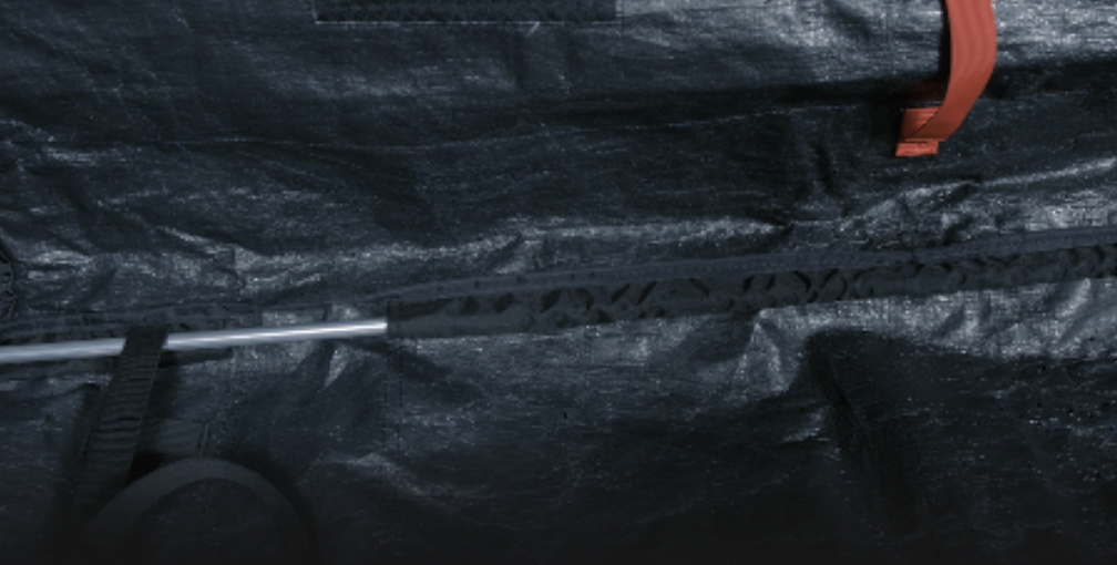 Nahaufnahme der dunklen Planenaußenseite einer Boardbag mit rotem Zipper und Kordel