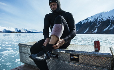 Surfer in a wetsuit carrying a surfboard down the beach