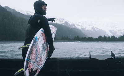 Surfer mit Neoprenschuhen, Handschuhen und Haube